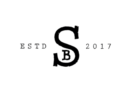 Close-up of a black logo or symbol with a circular design and stylized elements, on a black background.
