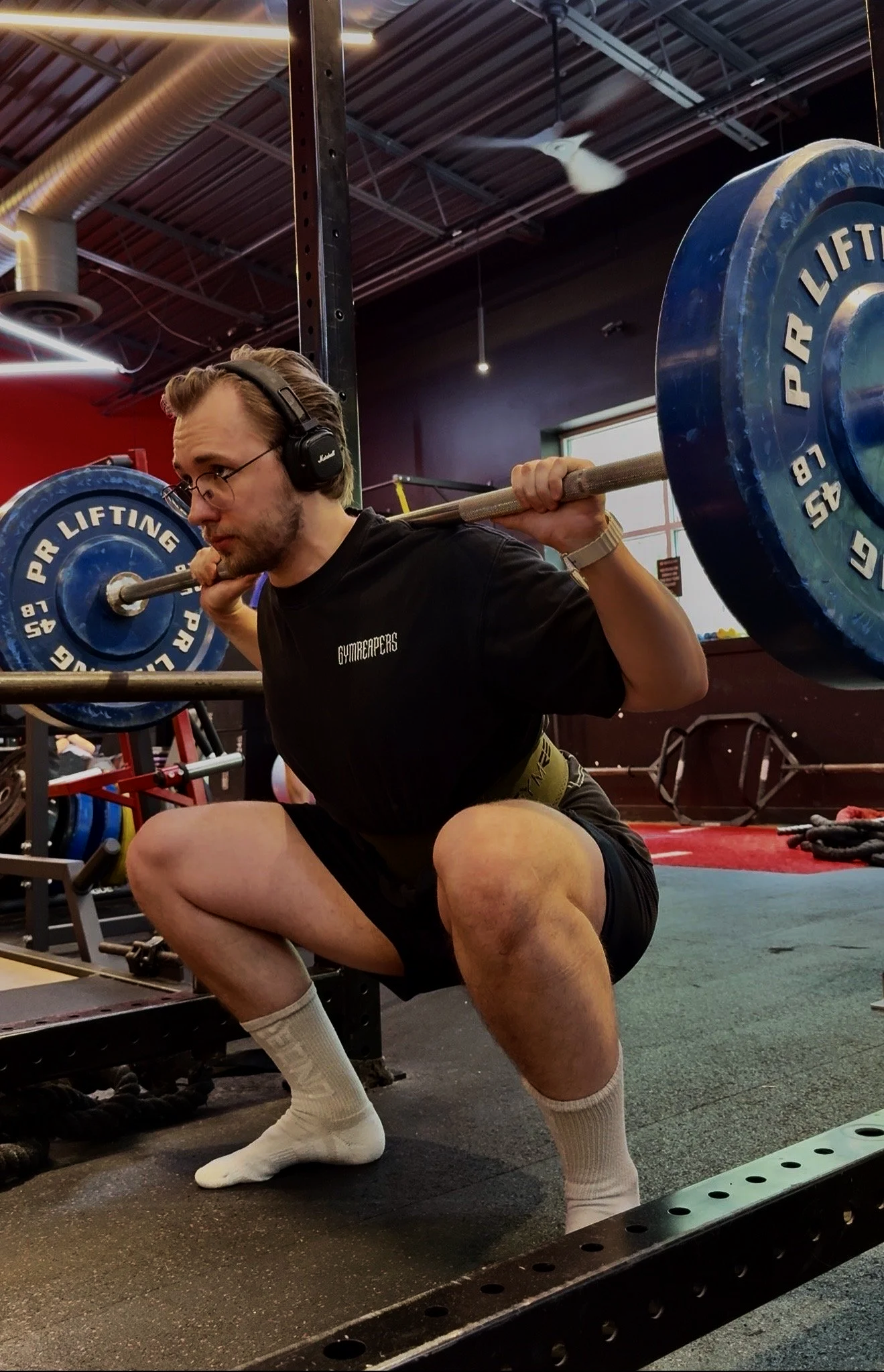 Personal trainer Bohdan Melnyk performing a barbell back squat during a strength training workout.