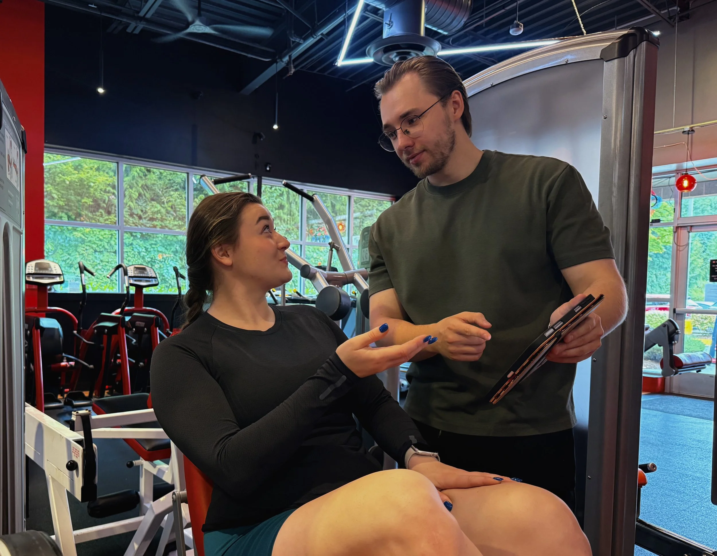 Personal trainer Bohdan Melnyk discussing a personalized workout with a client at the gym.