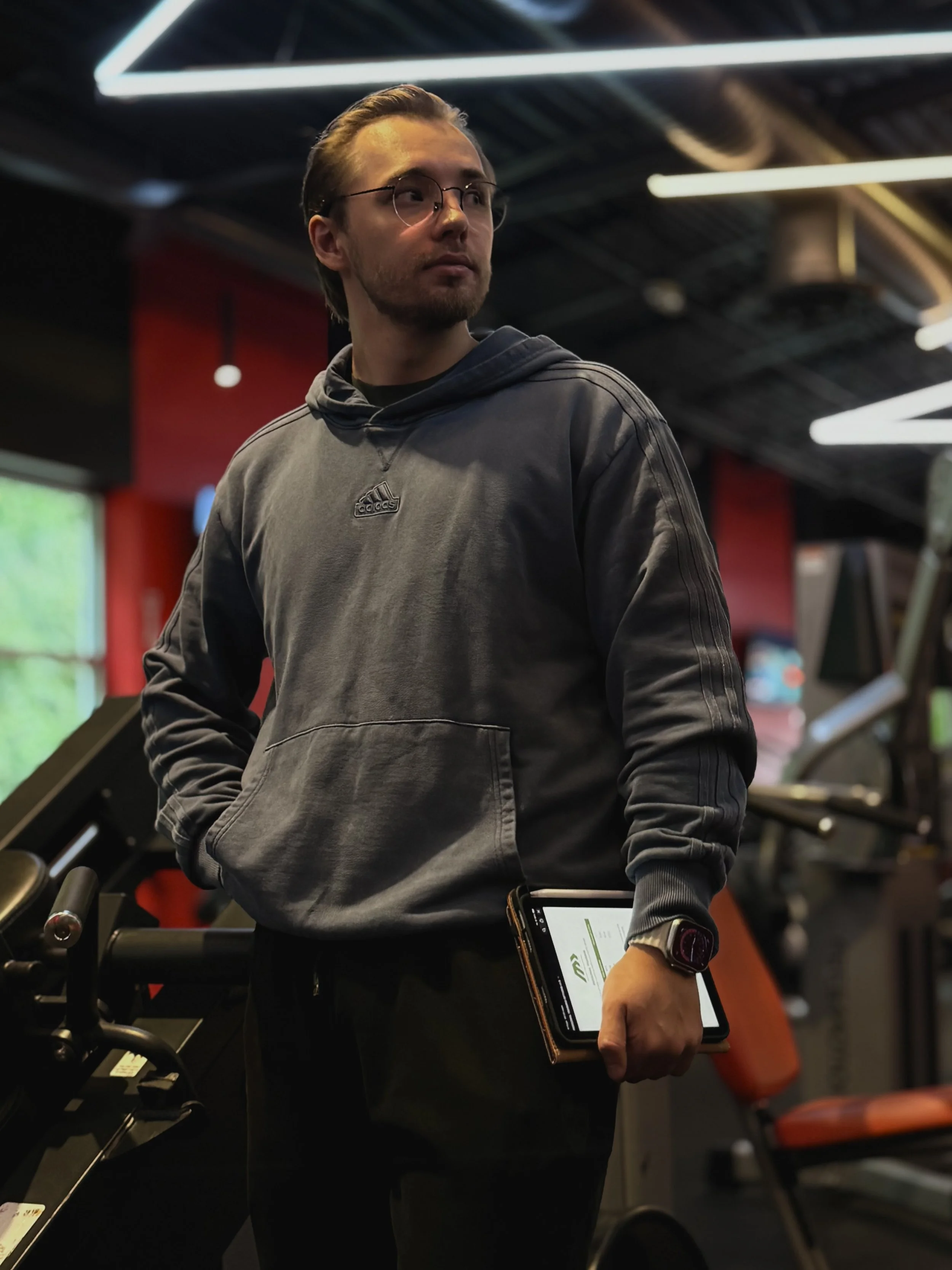 Personal trainer Bohdan Melnyk holding a tablet, with MELNYK logo, while preparing for a training session at the gym.