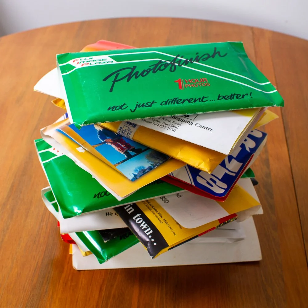 A stack of assorted magazines and brochures on a wooden table.