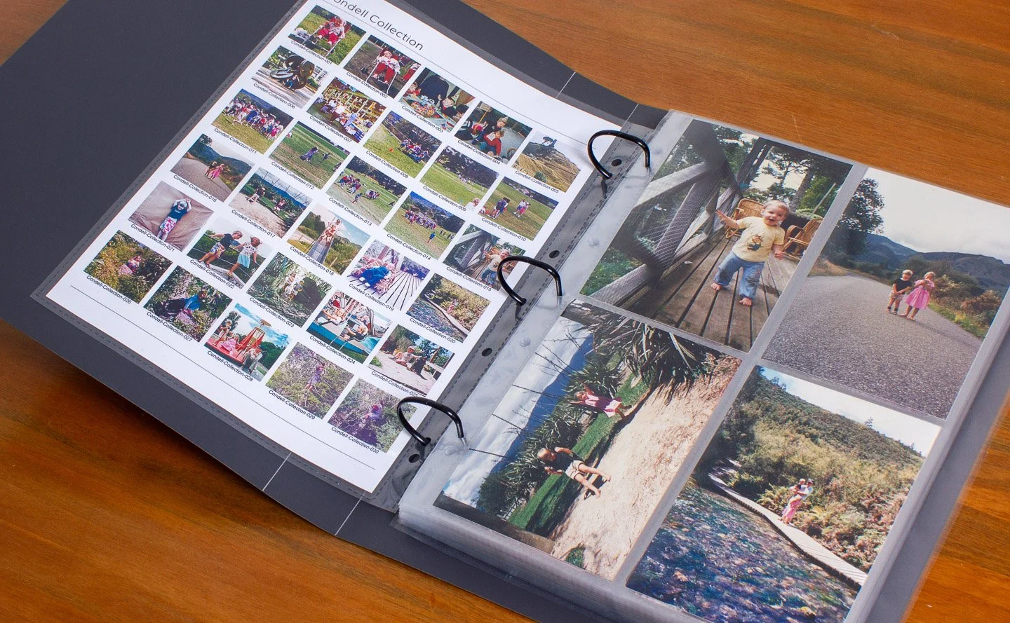 Open photo album on a wooden surface, displaying multiple photos of children playing outdoors and a contact sheet displaying the albums contents with digital filenames.