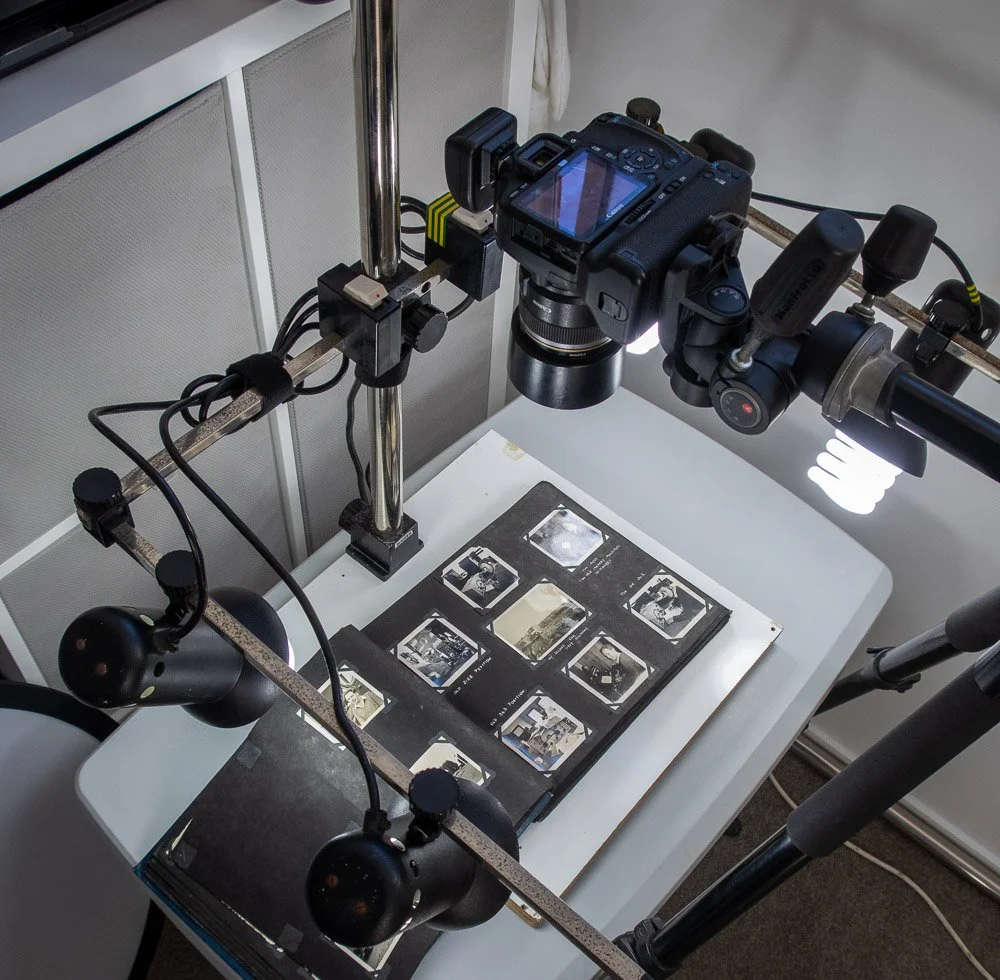 A camera mounted on a rig setup for photographing slides or negatives, with a lightbox underneath displaying the images.