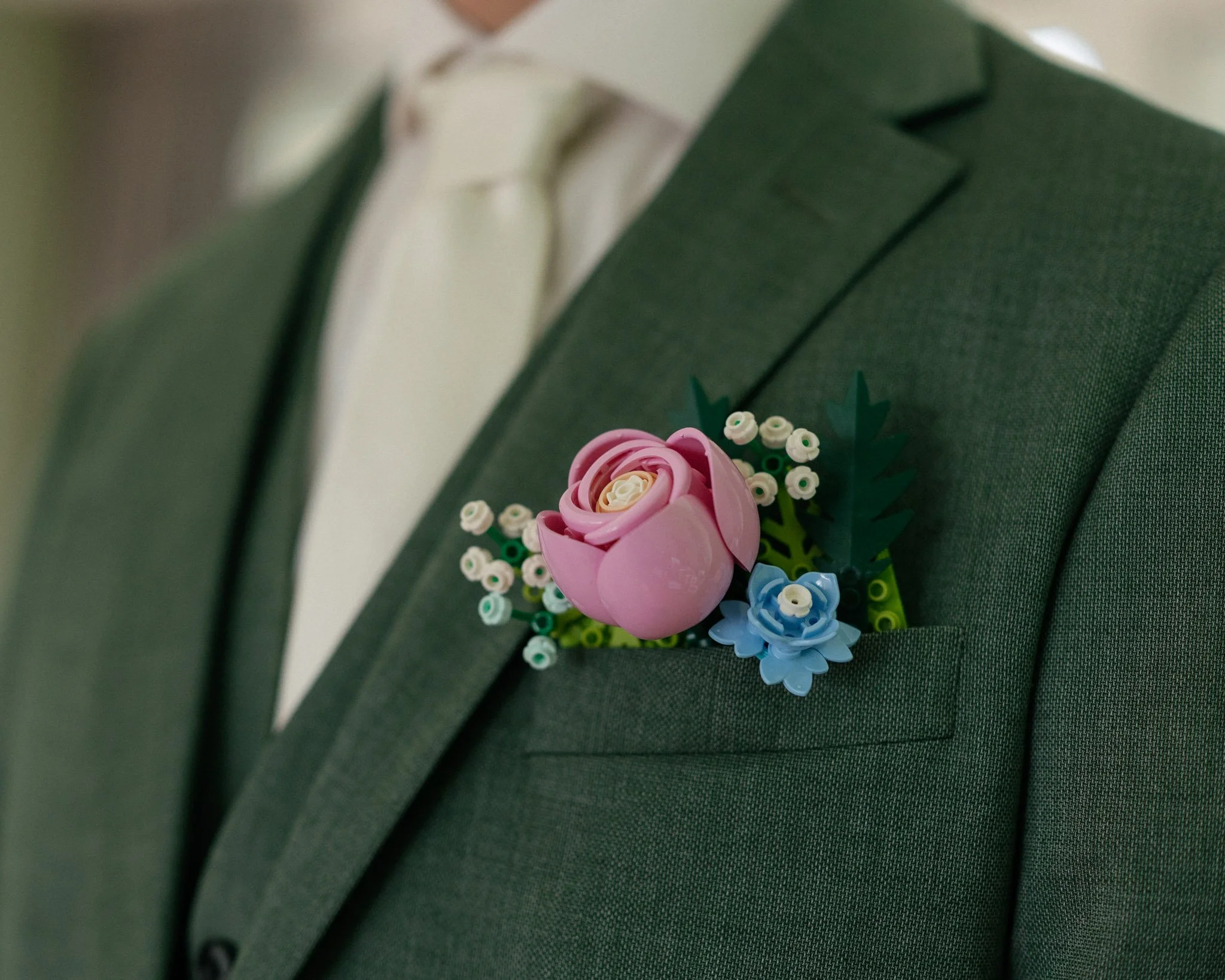Close-up of a grey suit jacket with a pink and blue flower boutonniere on the lapel.