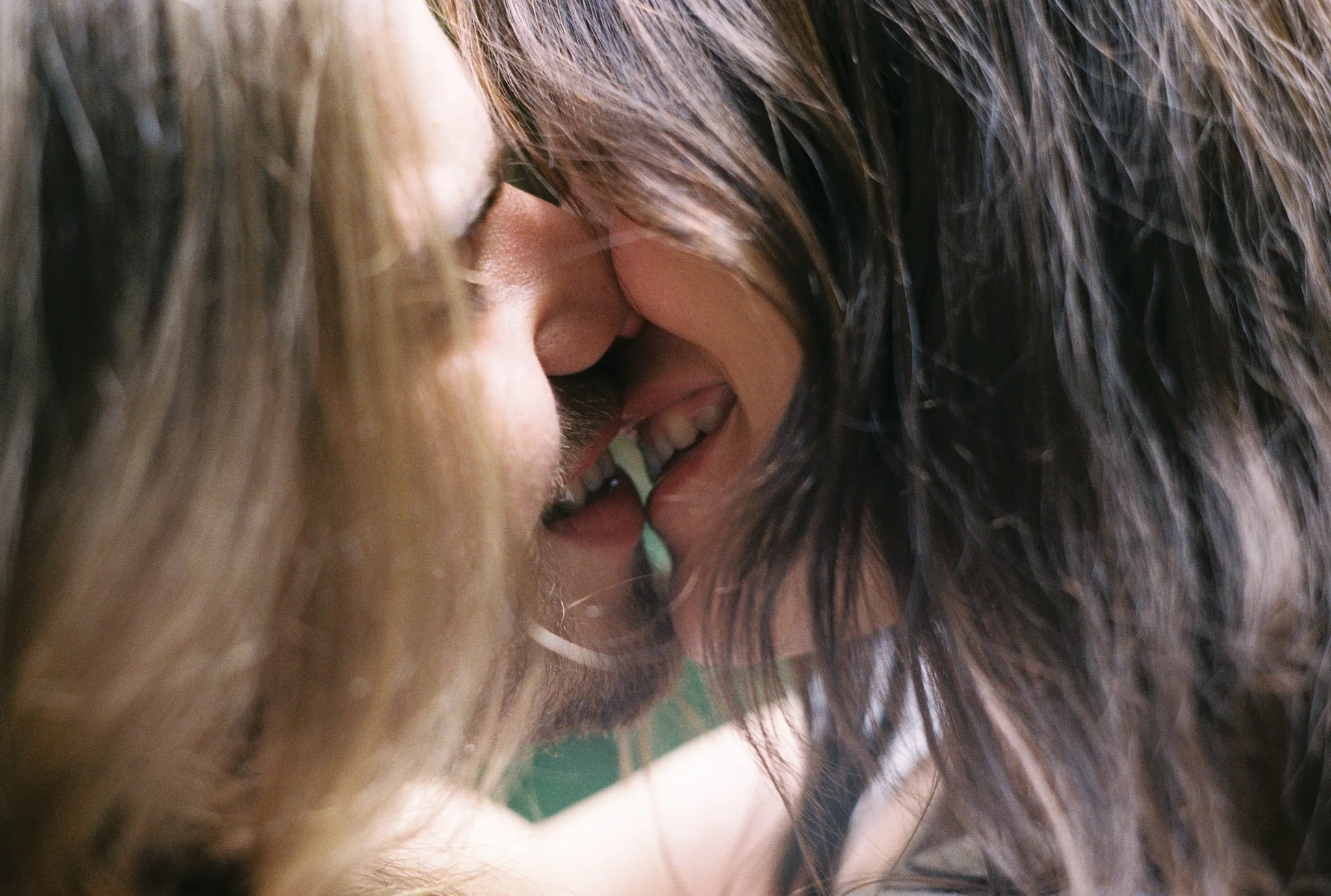 Close-up of two people whispering or sharing a secret, with their faces close together and smiling.