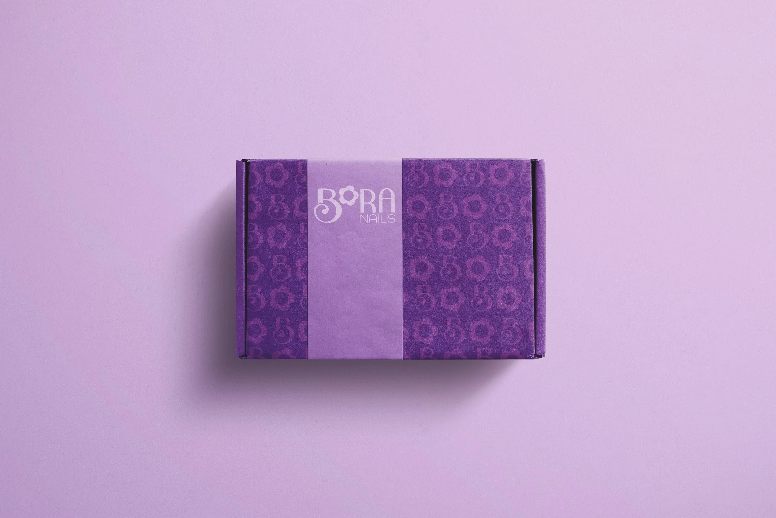 A purple box with the brand name 'BORA NAILS' on it, placed against a light purple background.