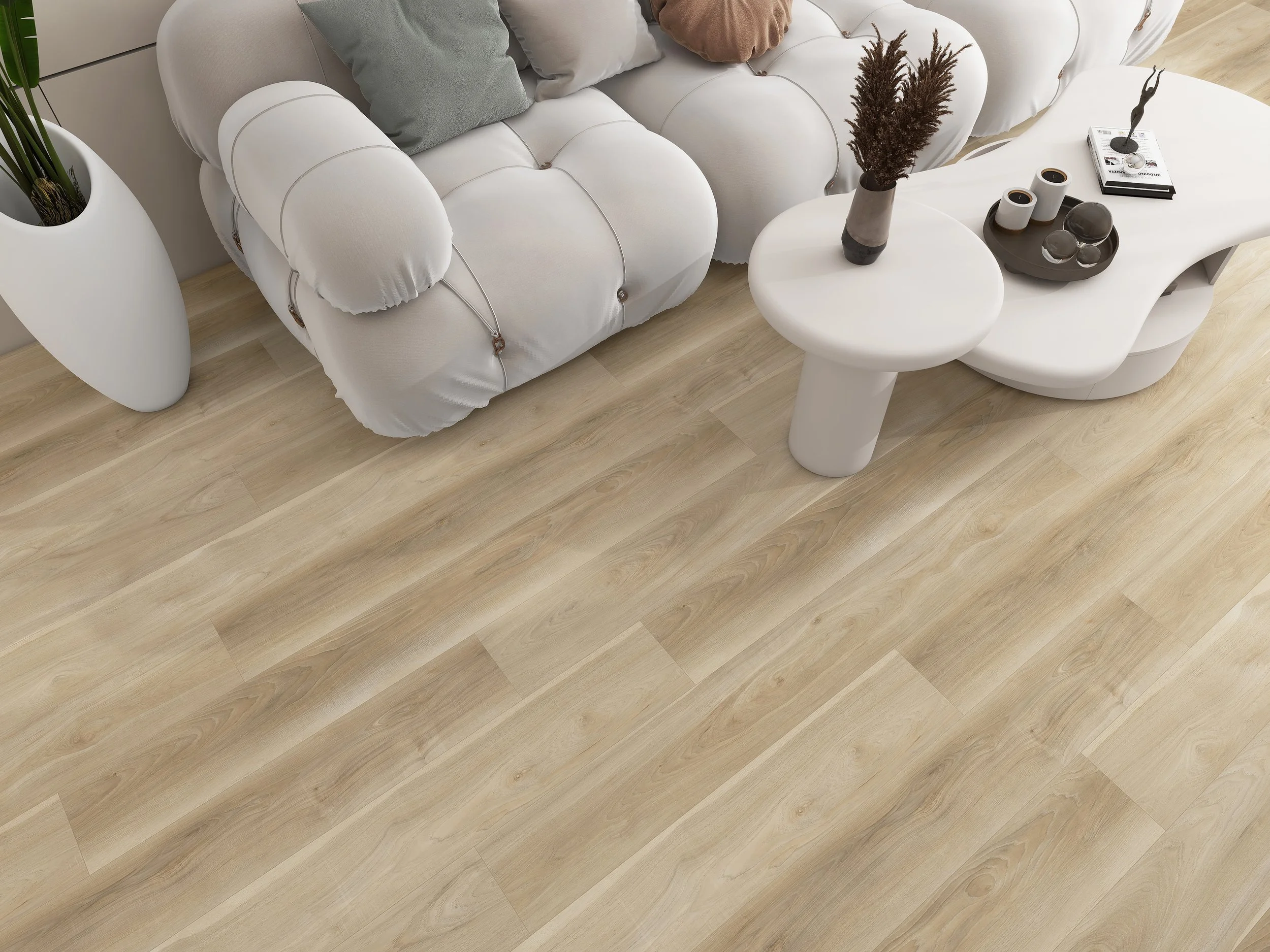 Living room with a white sofa, beige cushions, a white side table with a brown vase and dried plants, three tea cups, a black sculpture, and a magazine on a tray. The floor is light wood.