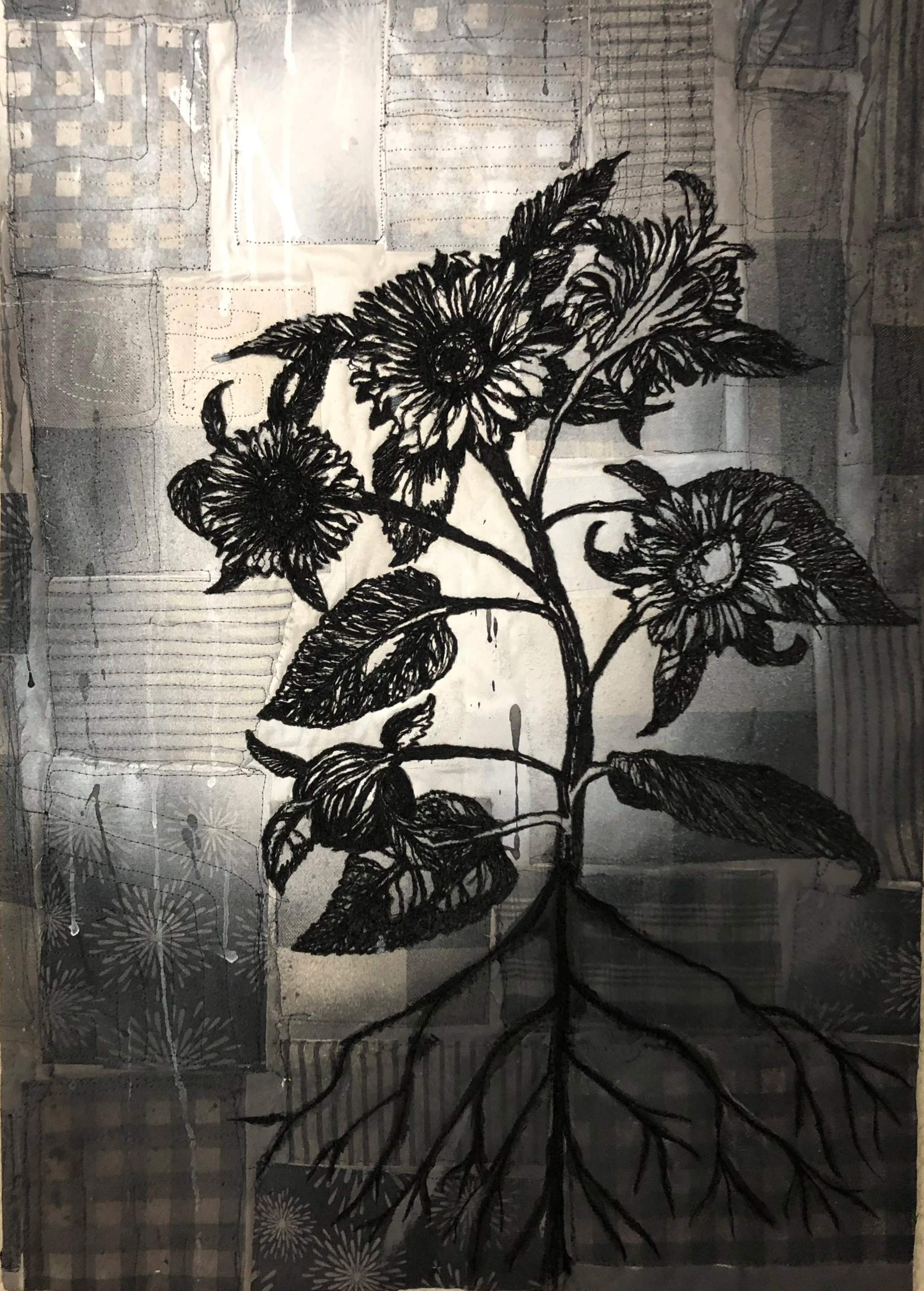 Black and white thread painting of a sunflower plant with large flowers and leaves, set against a background of patterned quilt squares.