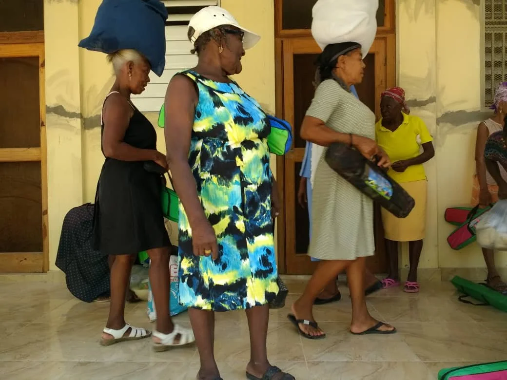 A Community Food Distribution for a Group of women carrying bags and items on their heads.