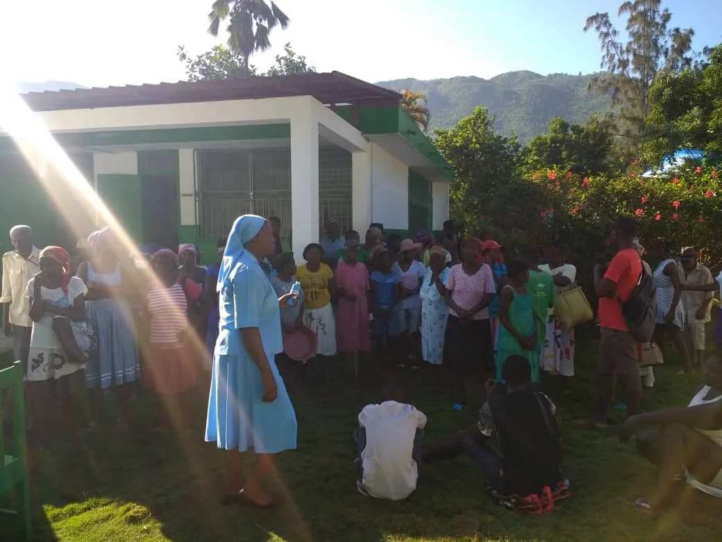 Sr Judith with a Group of people gathered outside the Baradères Hospital for a community Food Distribution for Elderly people. 