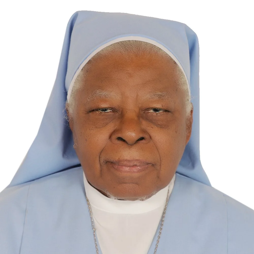 Close-up of an elderly Haitian woman dressed as a nun, wearing a light blue habit and veil, with a gentle expression.