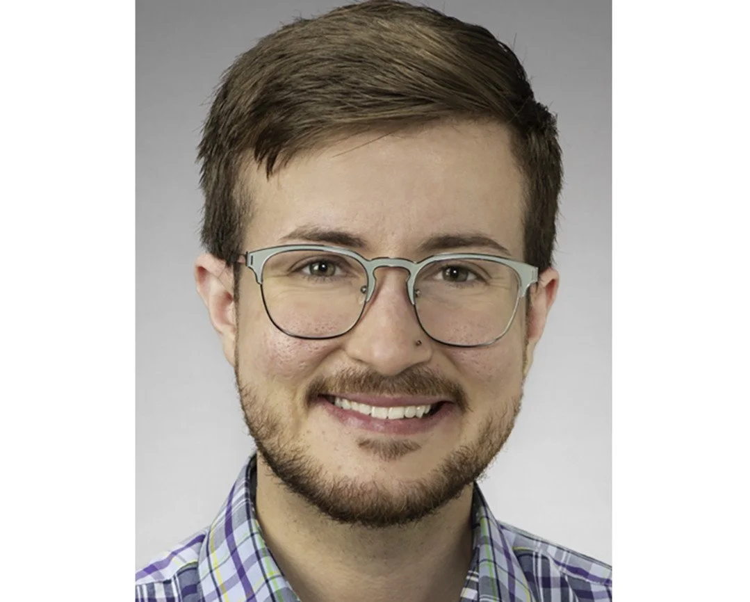 Headshot of Dr. Edmiston. He has short brown hair, glasses, and a beard, smiling at the camera, wearing a plaid shirt.
