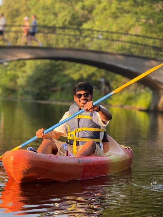 Photo of Shruthin smiling to camera, paddling a kayak. 