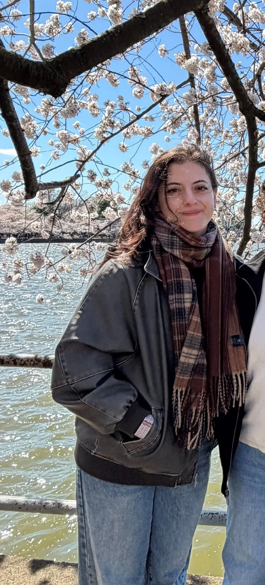 Photo of Paloma smirking to camera, standing in front of cherry blossom tree.