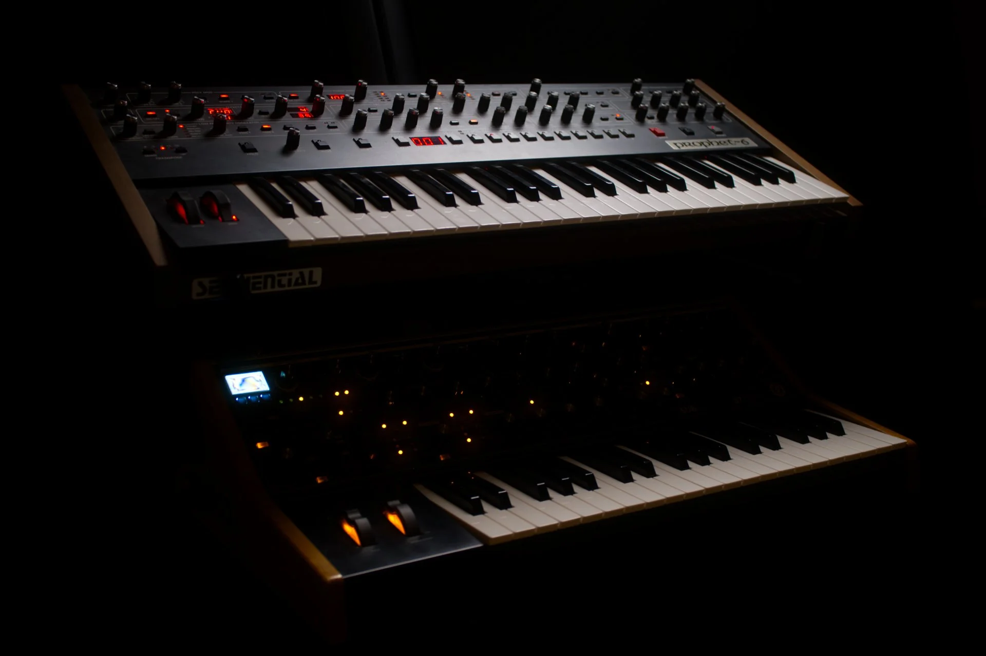 A digital music synthesizer with glowing controls and a keyboard, situated in a dark environment.