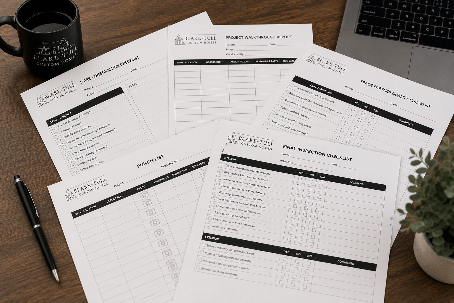 Construction checklists and project report forms on a wooden desk next to a black coffee mug with company logo, a silver pen, and a potted plant, along with a laptop keyboard.