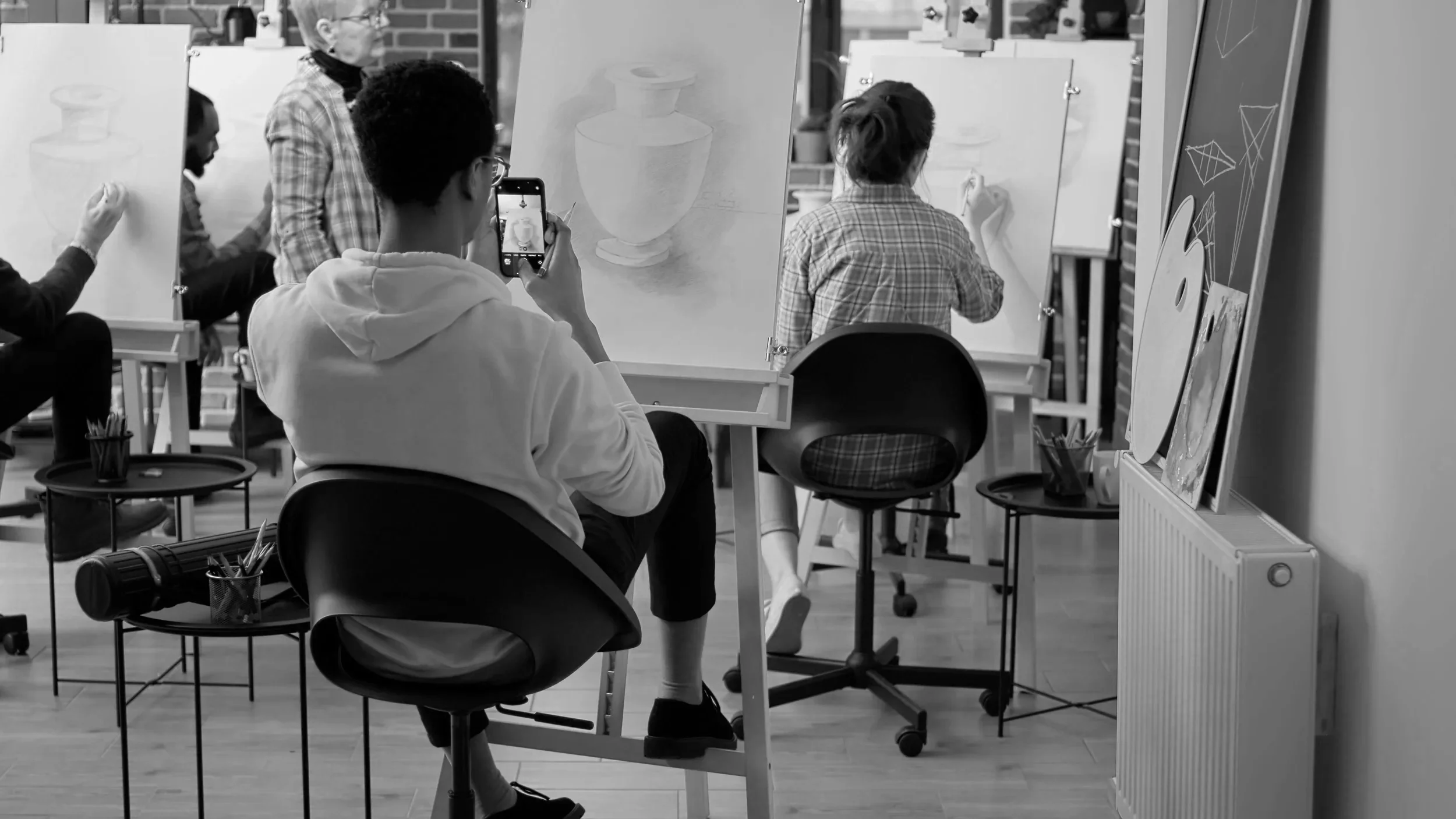 Black-and-white photo of a young student drawing at an easel.