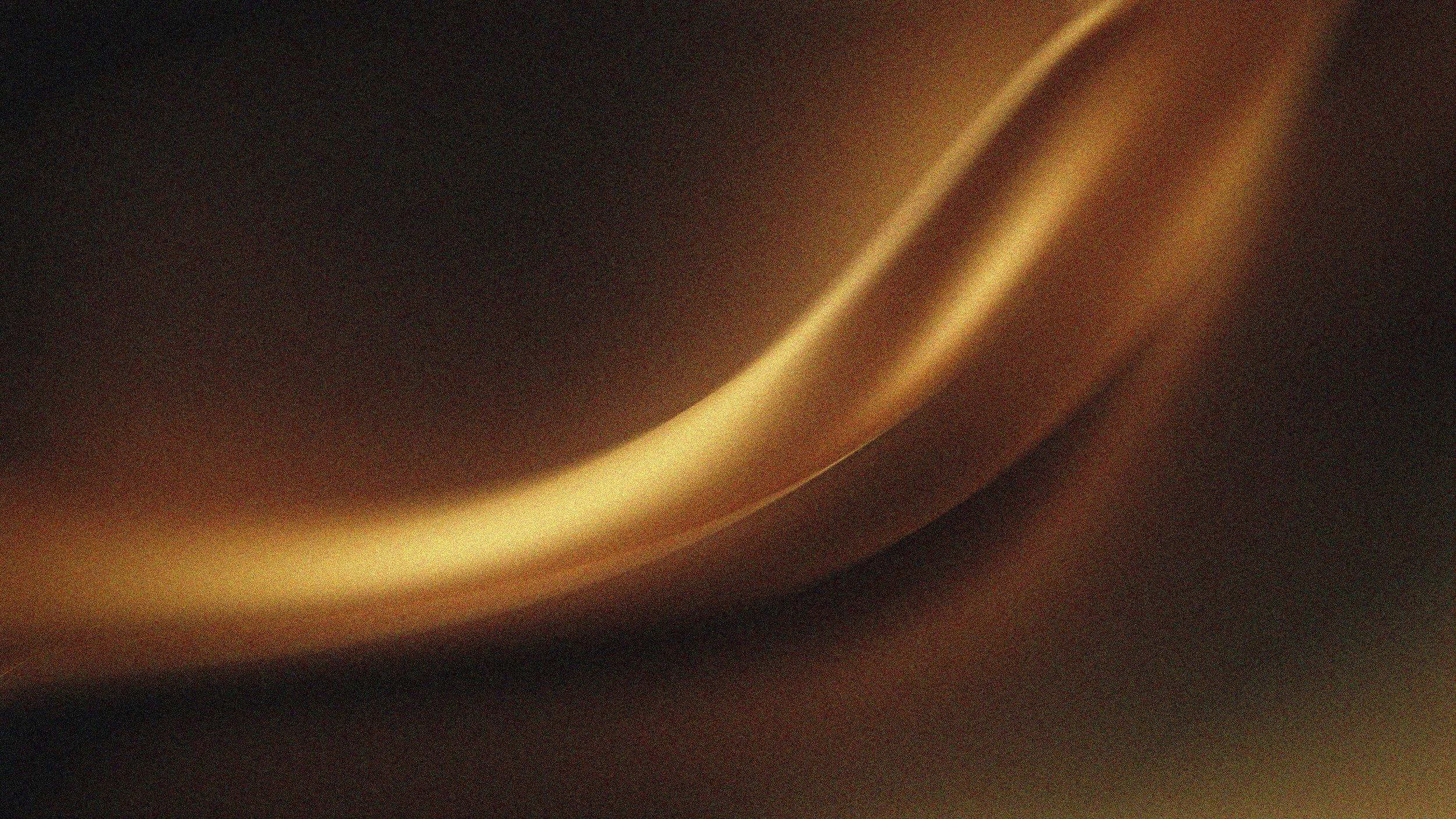 Close-up of a metallic, gold-colored curved surface with subtle reflections and shadows.