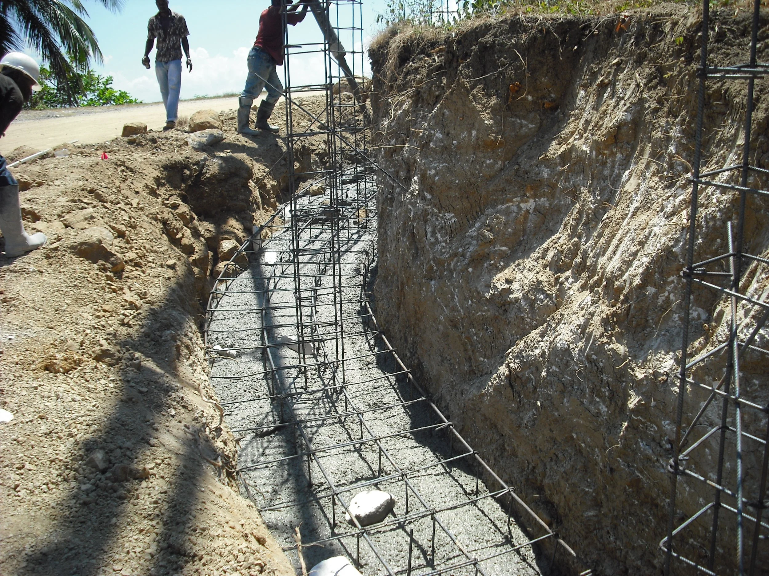 Construction workers build a reinforced concrete foundation in a trenchy.