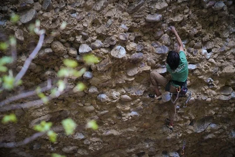 Person rock climbing on a steep, rocky outdoor cliff wall.