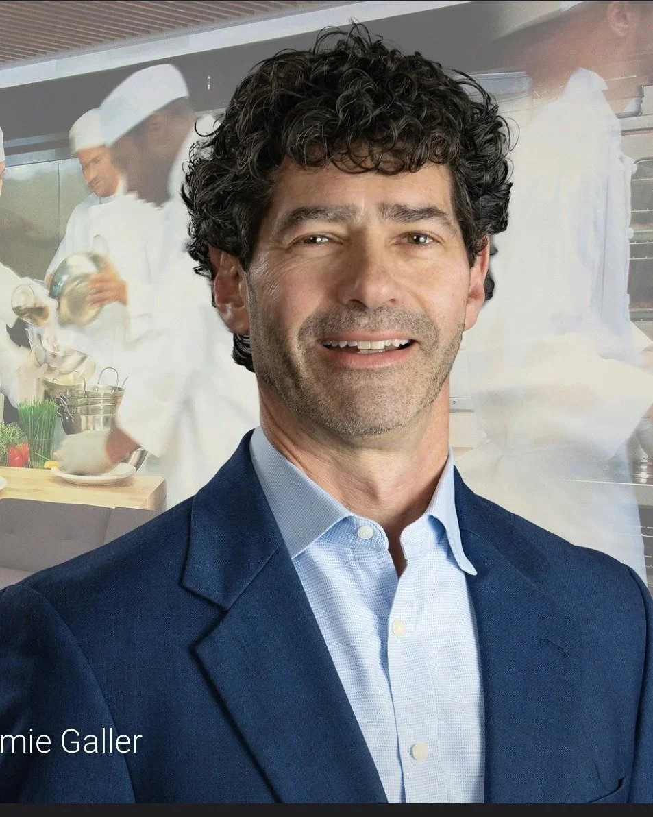 Portrait of Jamie Galler, founder of The Practical Creative, over a restaurant kitchen backdrop