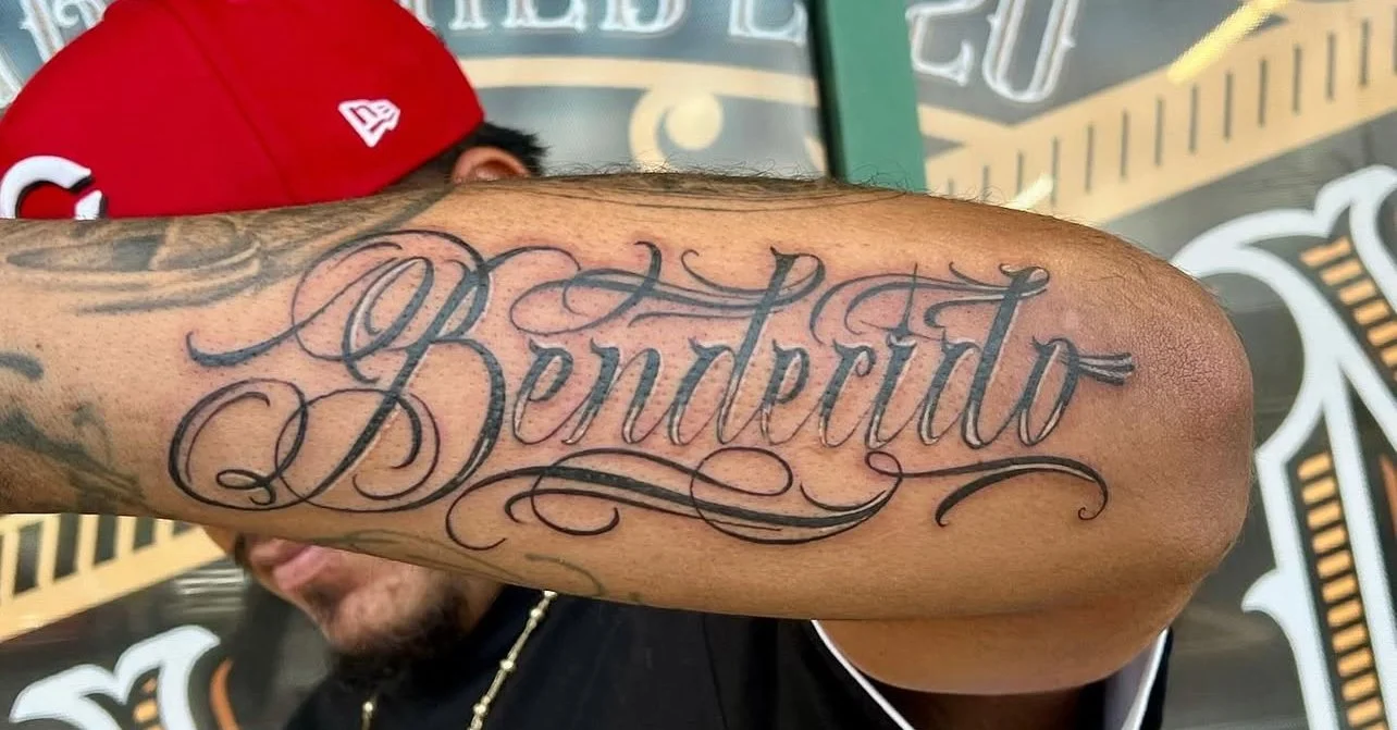 Close-up of a person's tattoo on their arm that reads 'Benjamin' in elaborate script.