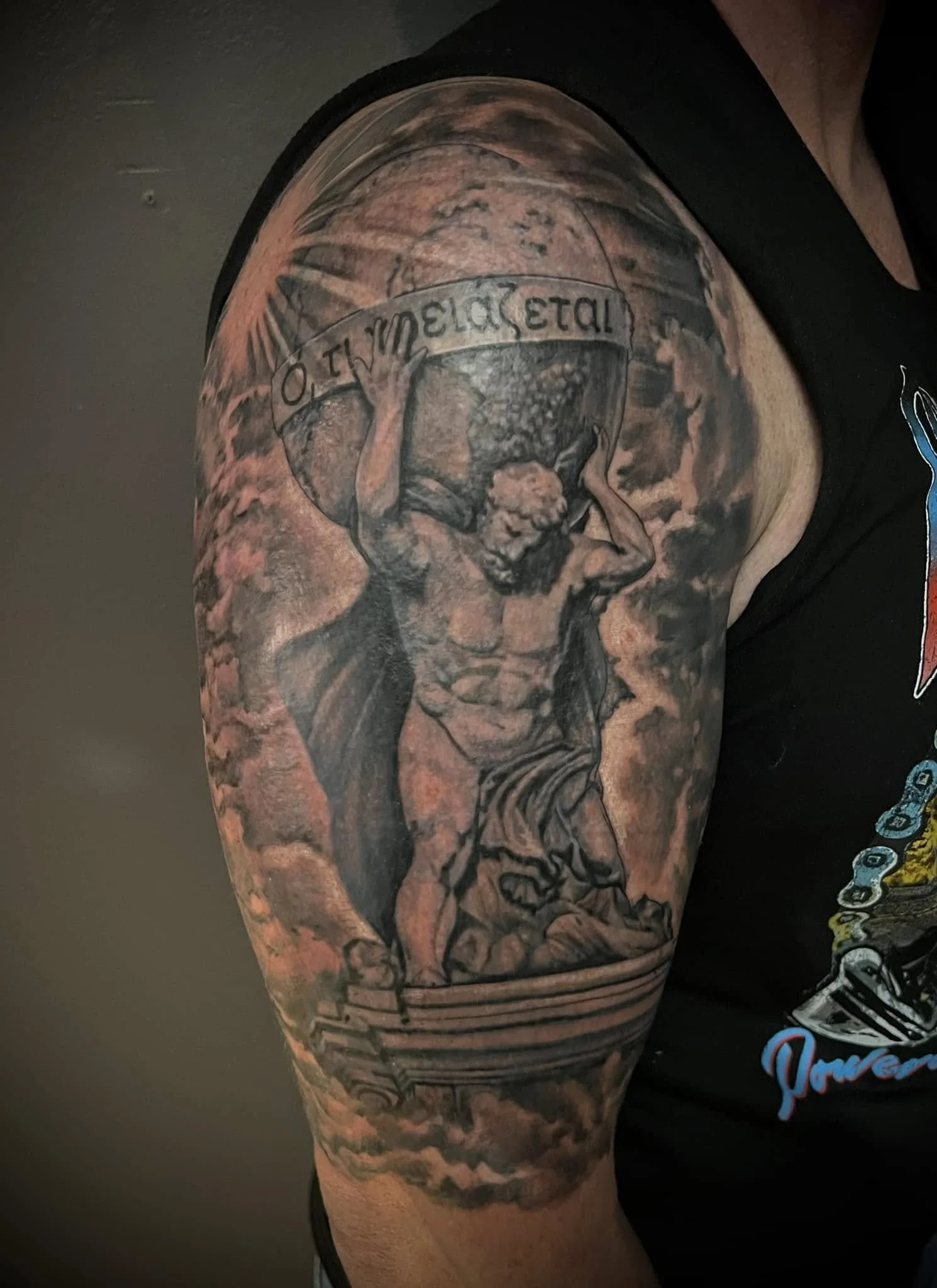 Tattoo of a woman with a sign that says 'METAL' on her head, on a person's upper arm.