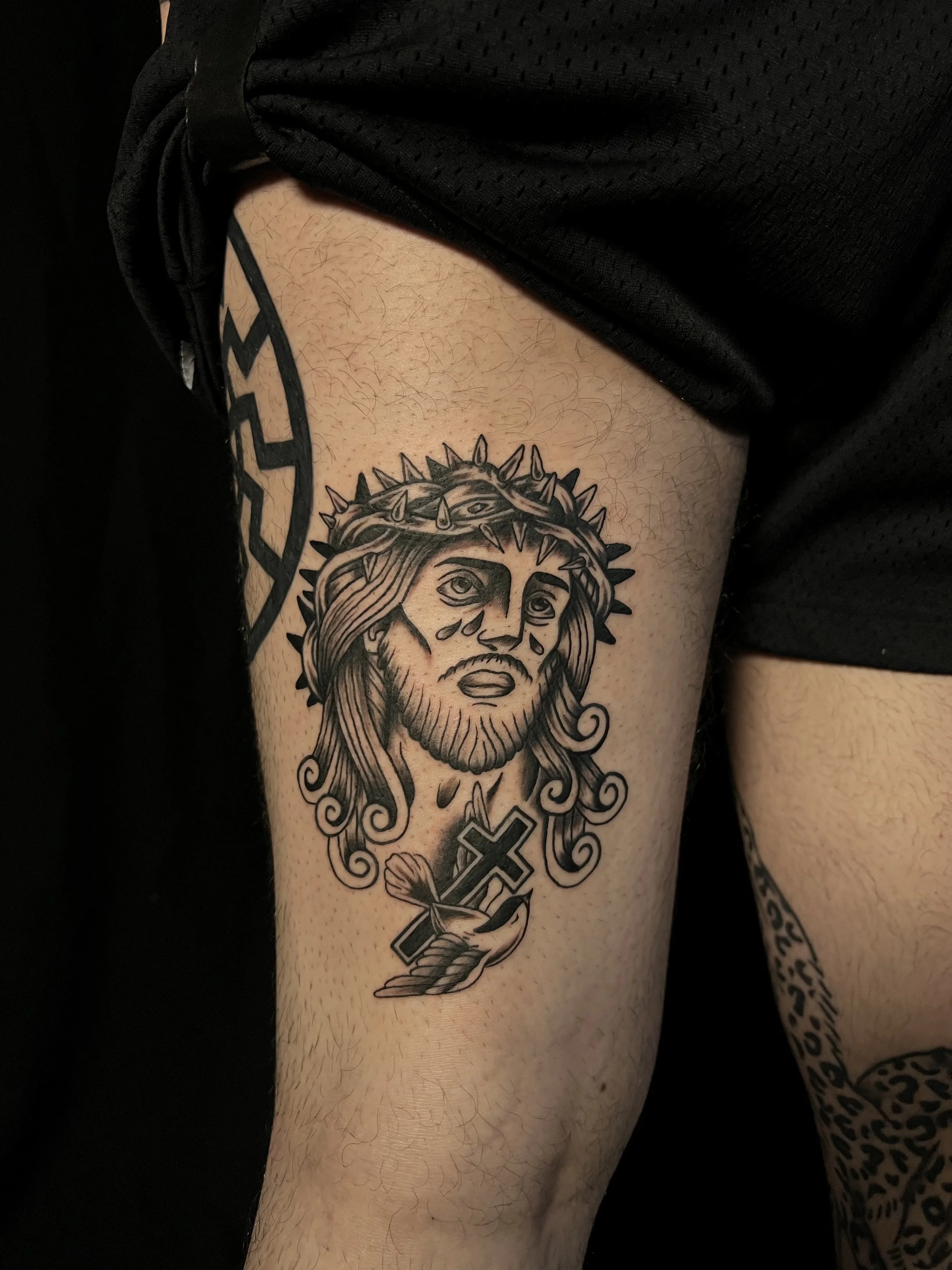 Tattoo of a woman with a crown of thorns and tears on her face, holding a cross with a ribbon.