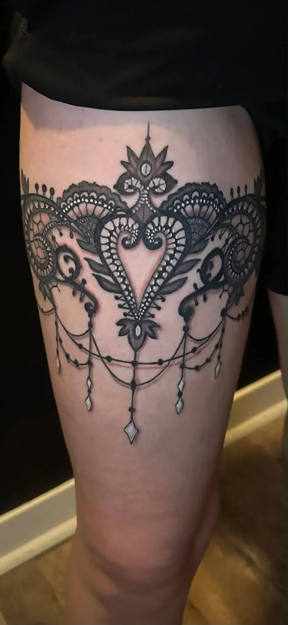 Black lace chandelier tattoo on upper thigh.
