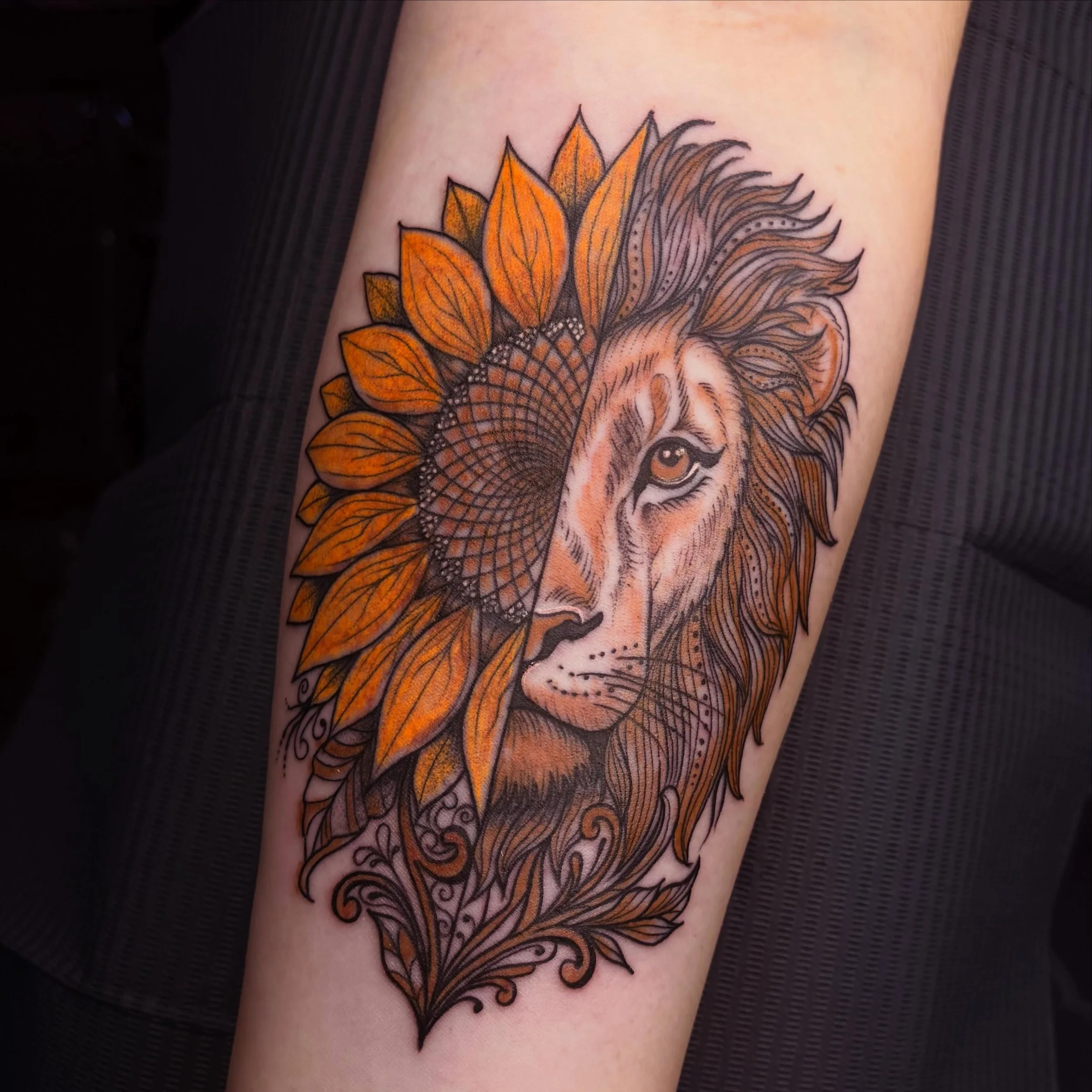 A tattoo of a lion's face surrounded by orange and yellow sunflower petals.