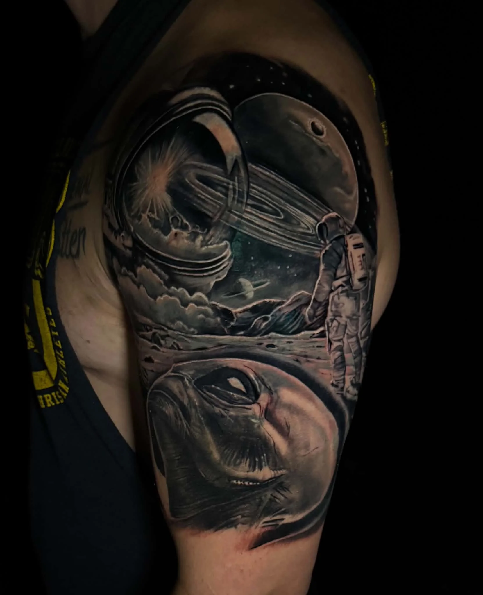 Close-up of a detailed tattoo on a person’s forearm, featuring a realistic depiction of a space scene including planets, Saturn with rings, a spaceship, stars, and a cosmic background.