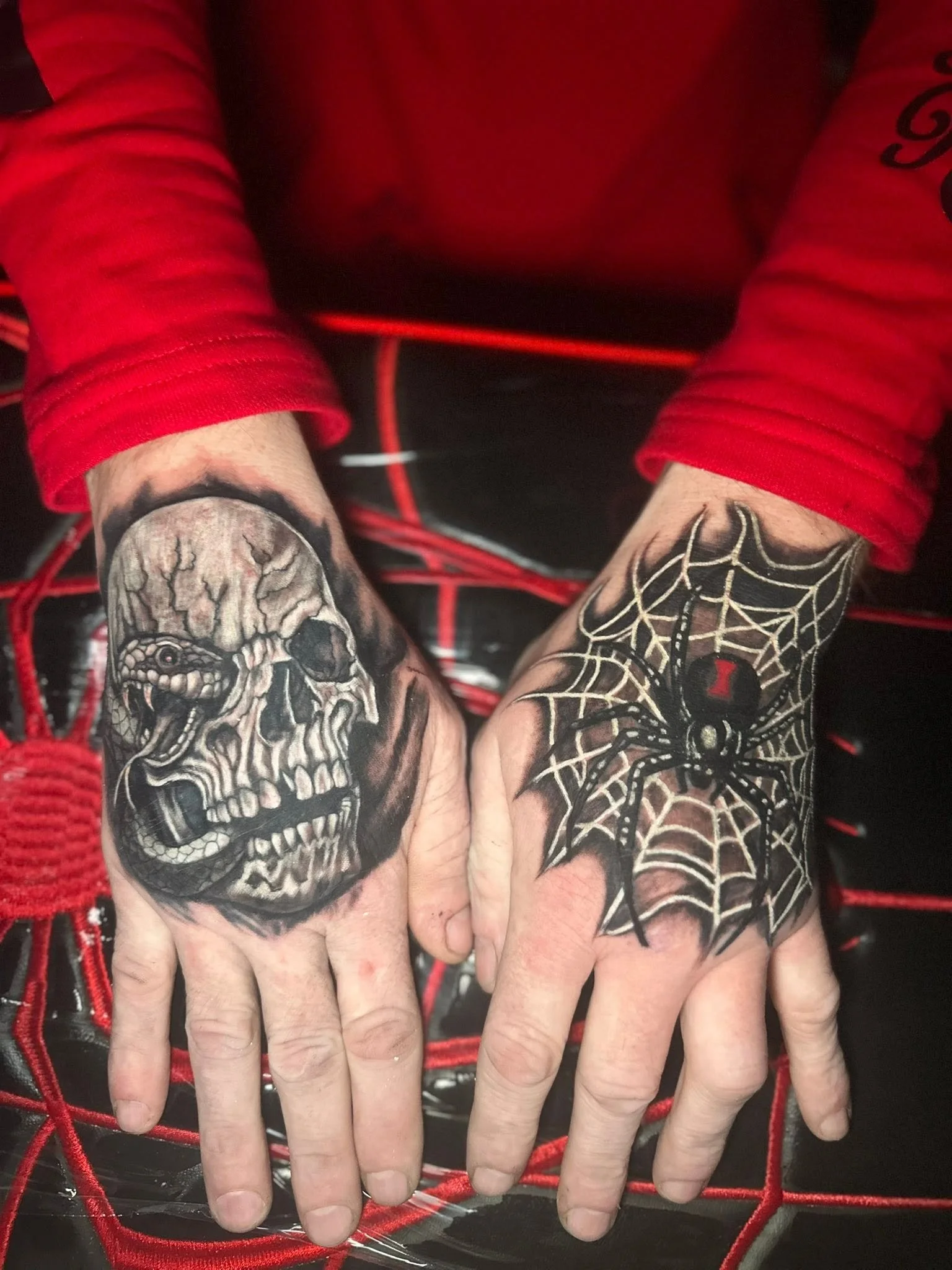 Close-up of two hands with tattoos resting on a red and black net.