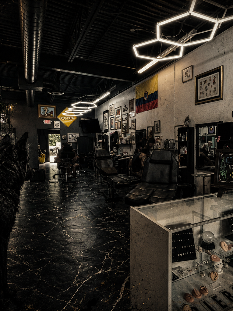 Interior of a tattoo studio with black marble flooring, leather chairs, framed artwork on the walls, and modern light fixtures.