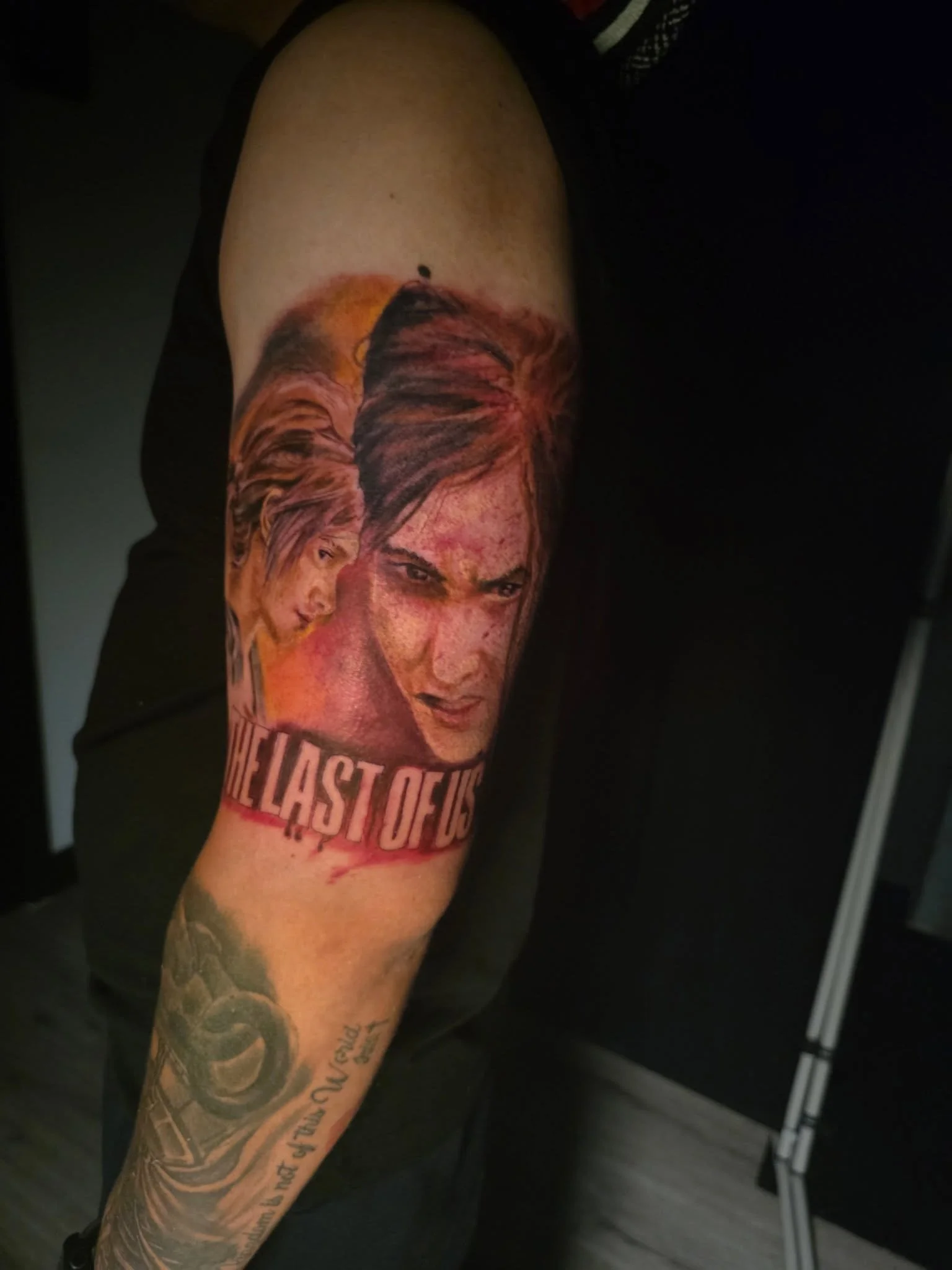 Tattoo of a woman's face with long hair and the phrase "The Last of Us" on a person's arm.