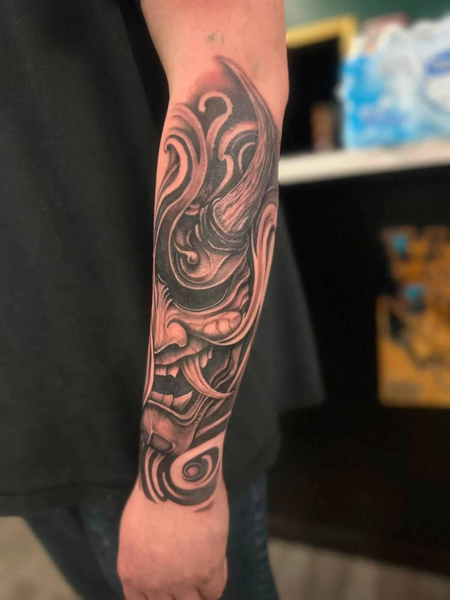A person's arm with a black and pink tattoo featuring swirling, abstract patterns.