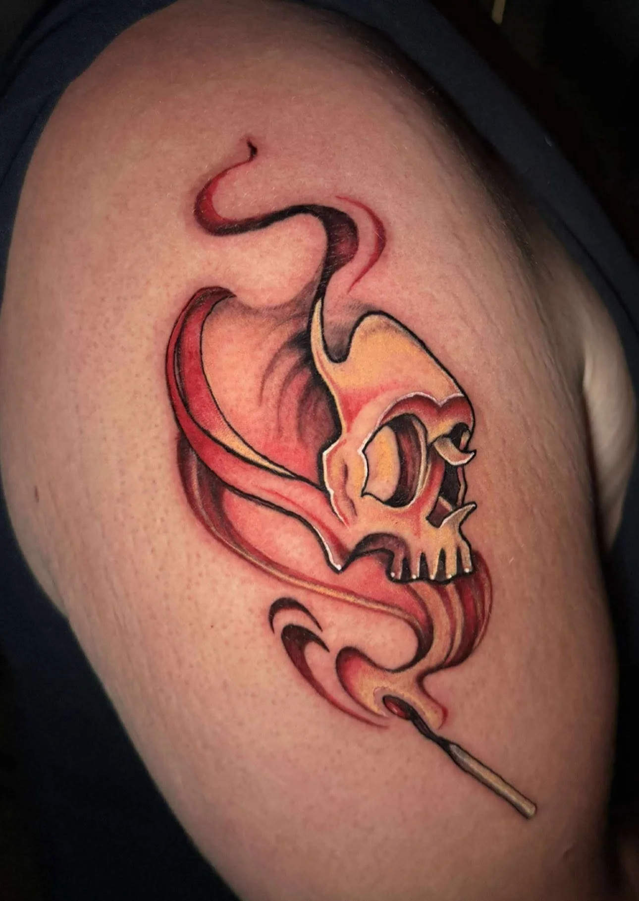 Tattoo of a human skull with smoke coming out of the skull, on a person's upper arm.