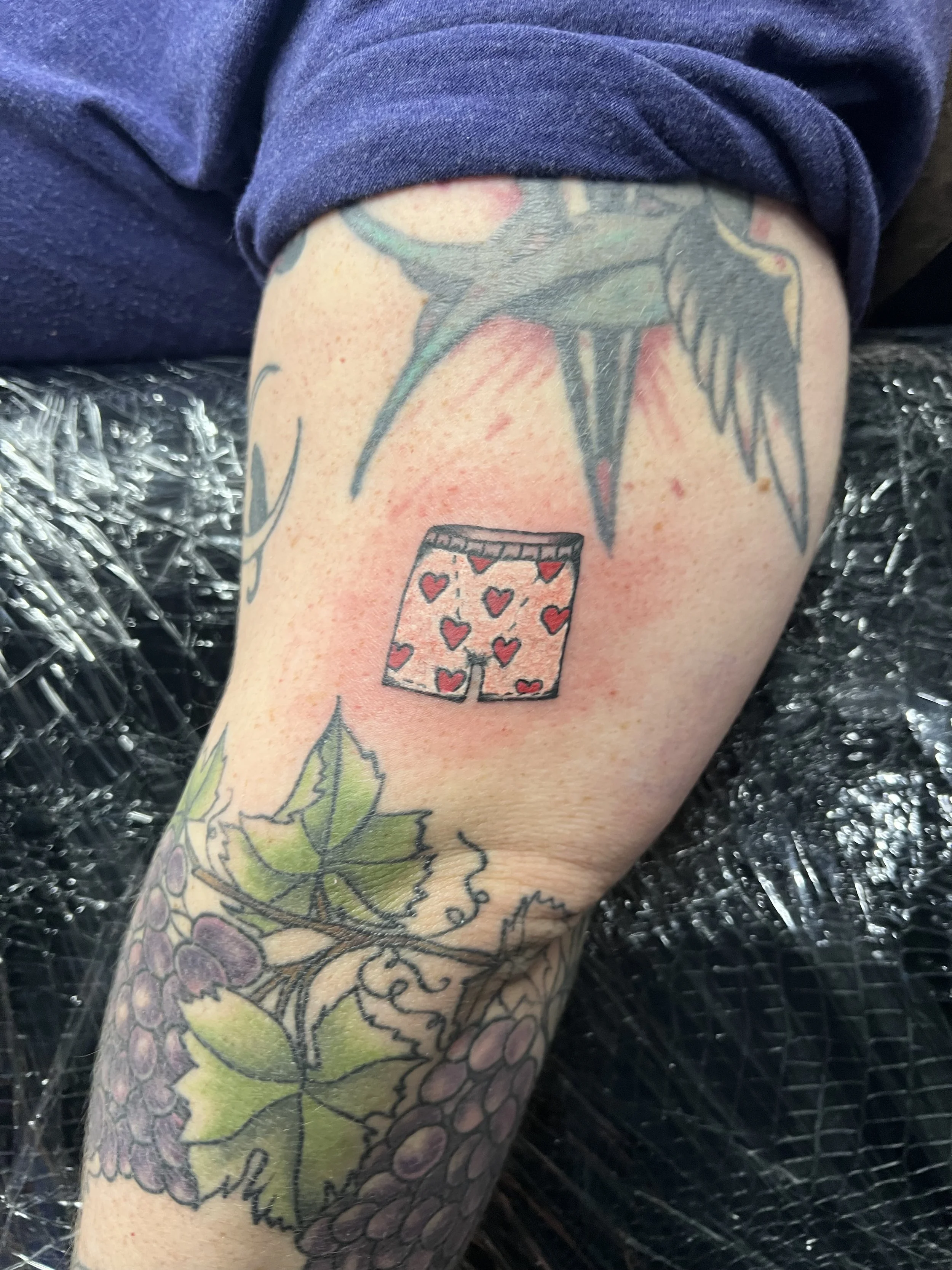Tattoo featuring a spray paint can with hearts as the design pattern on the can, located on a person's arm.