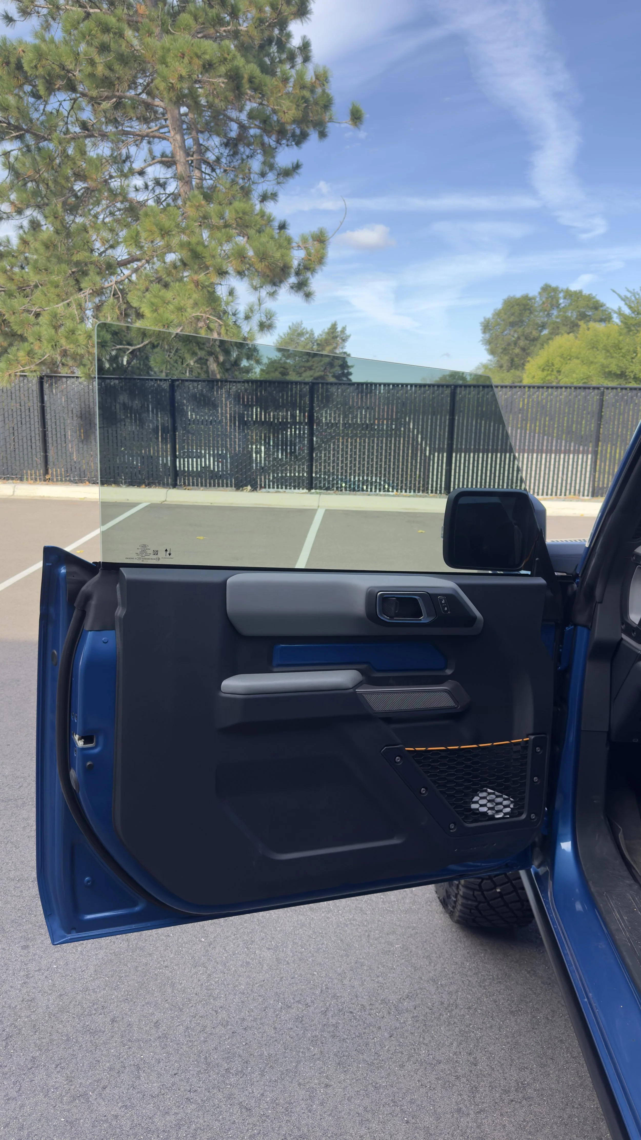 Tinted front side window on a blue Ford Bronco with the driver's door open