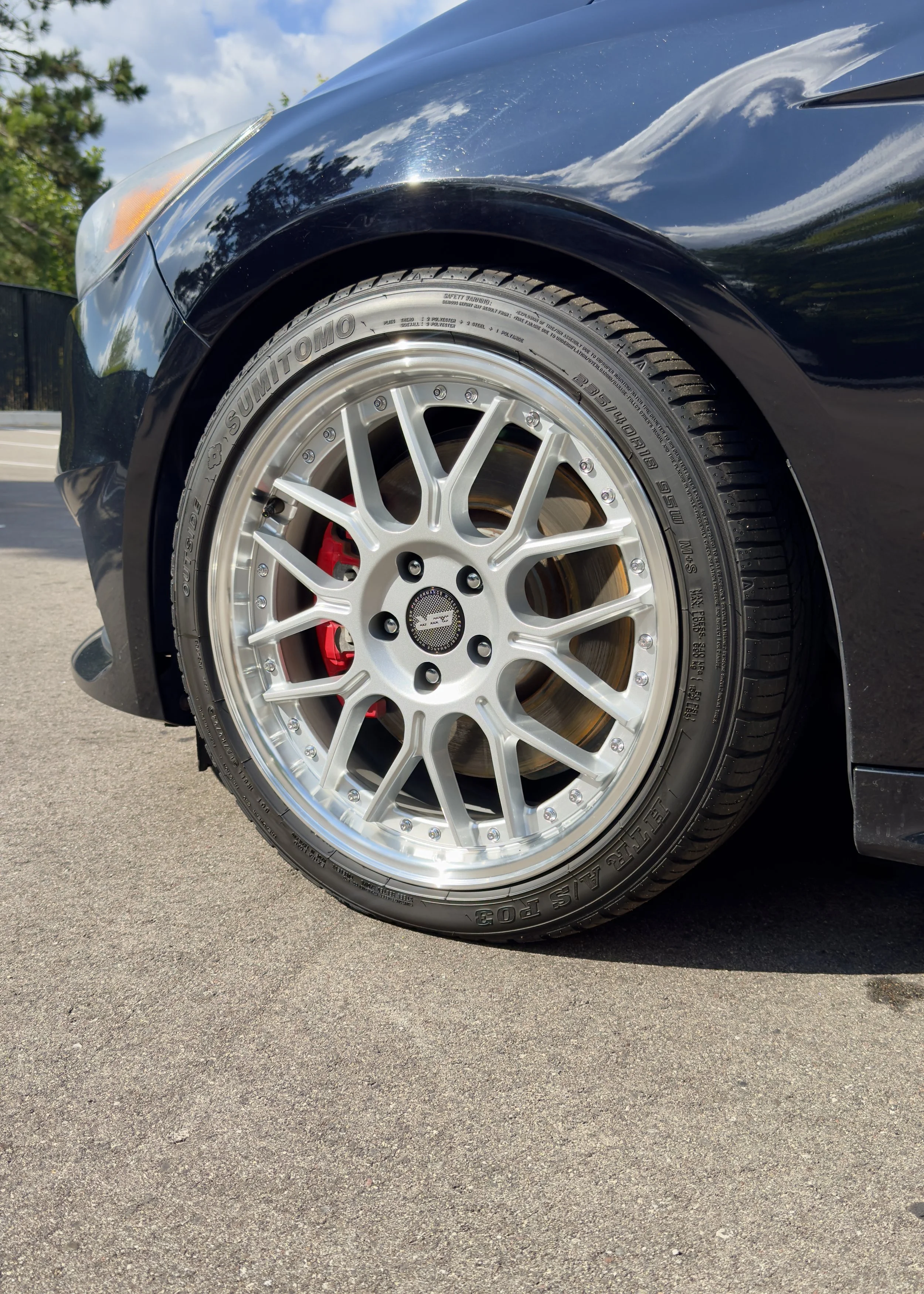 Close-up of an alloy wheel and red brake caliper on a black vehicle.