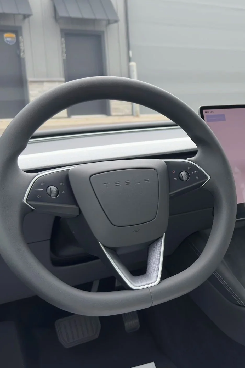 Tesla interior showing the steering wheel, dashboard, and center touchscreen.