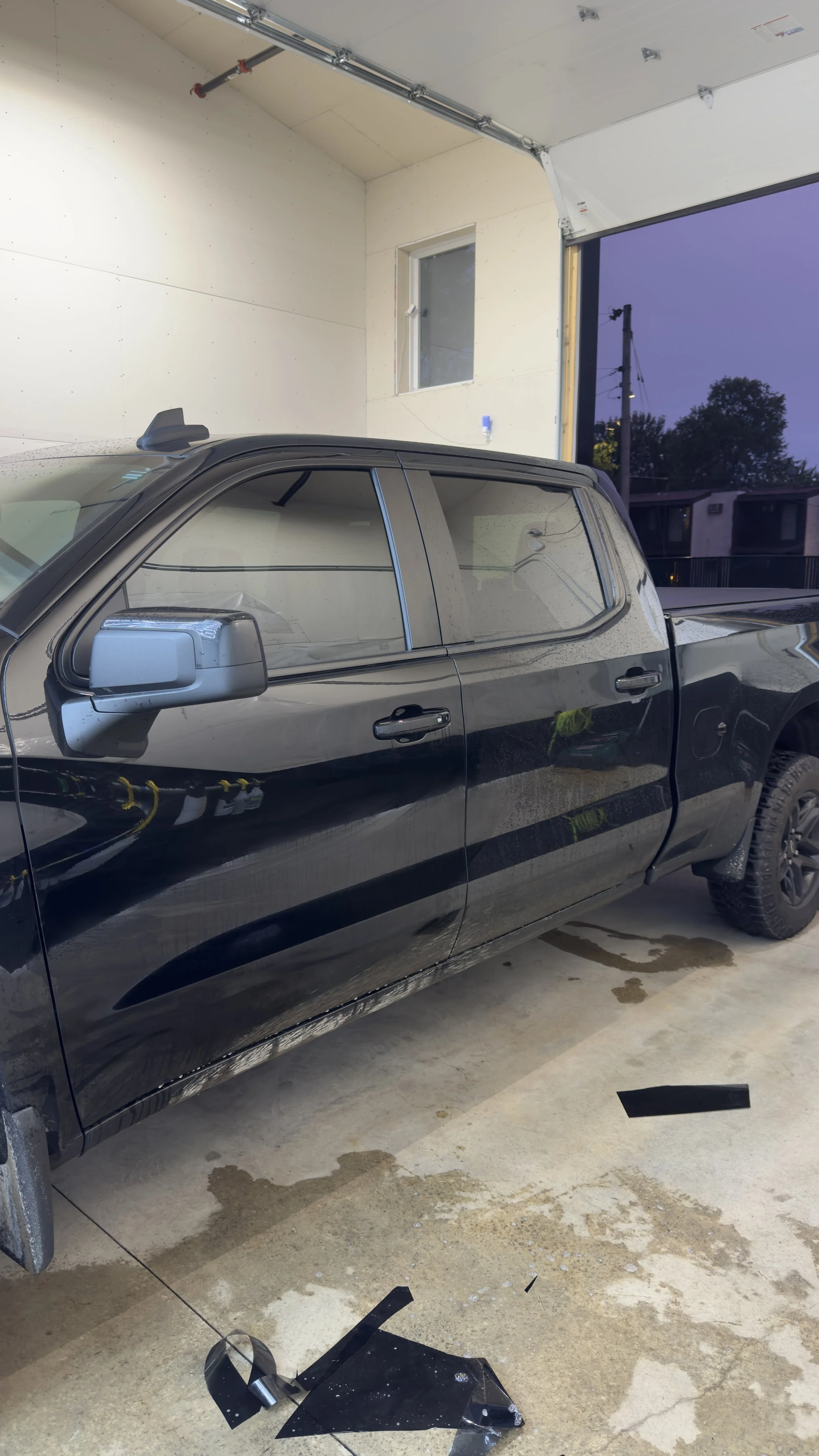 Black pickup truck with tinted side windows inside the shop