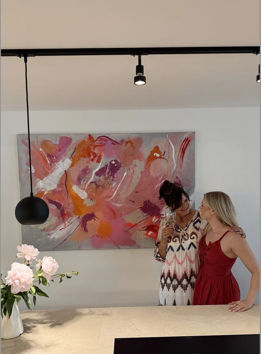 Artist Sabrina Richter with a collector in front of a large commissioned abstract painting in pink and orange