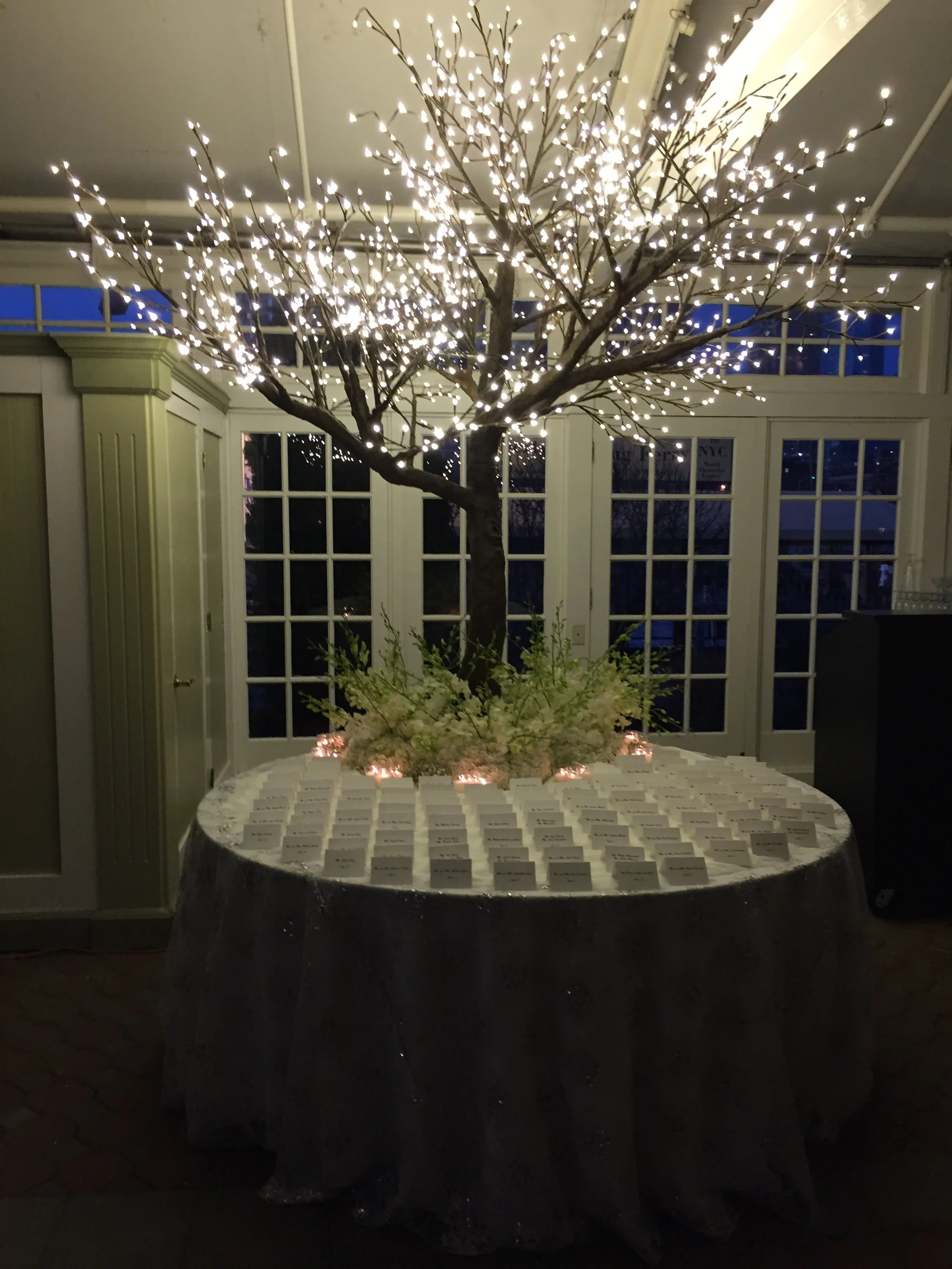 Table with place cards and a lit decorative tree in the background