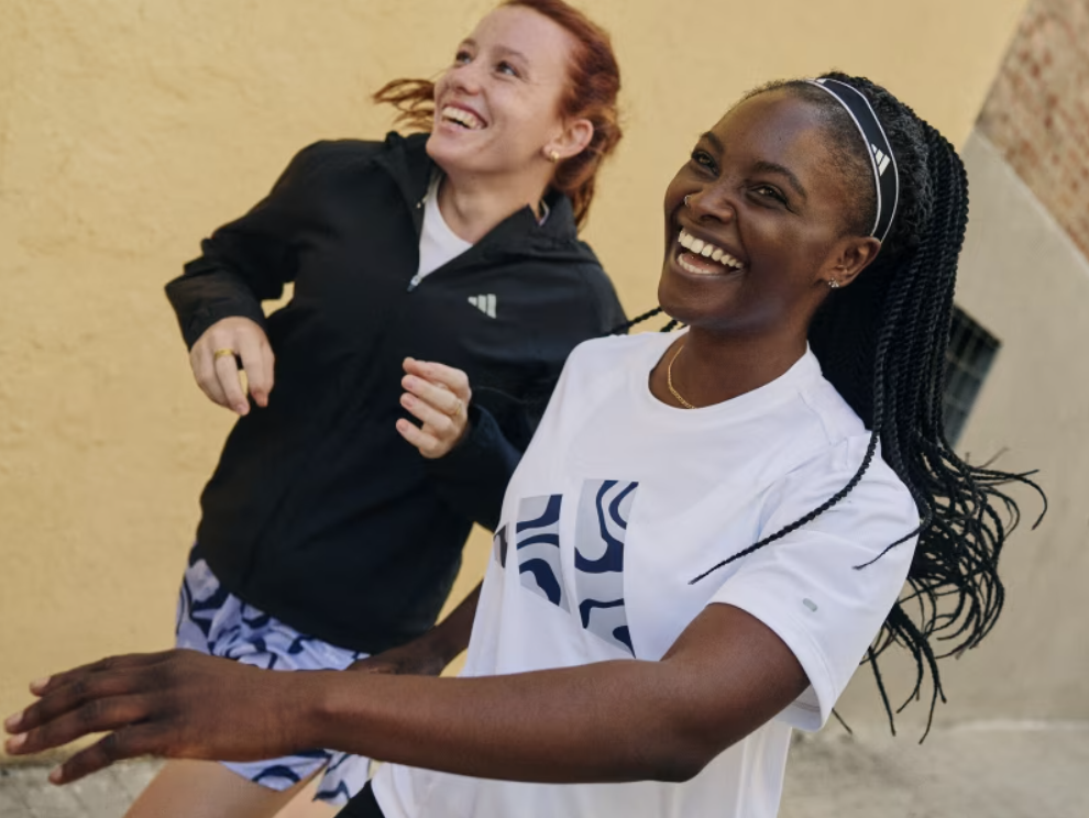 Two women with athletic outfits smiling and enjoying themselves outdoors.