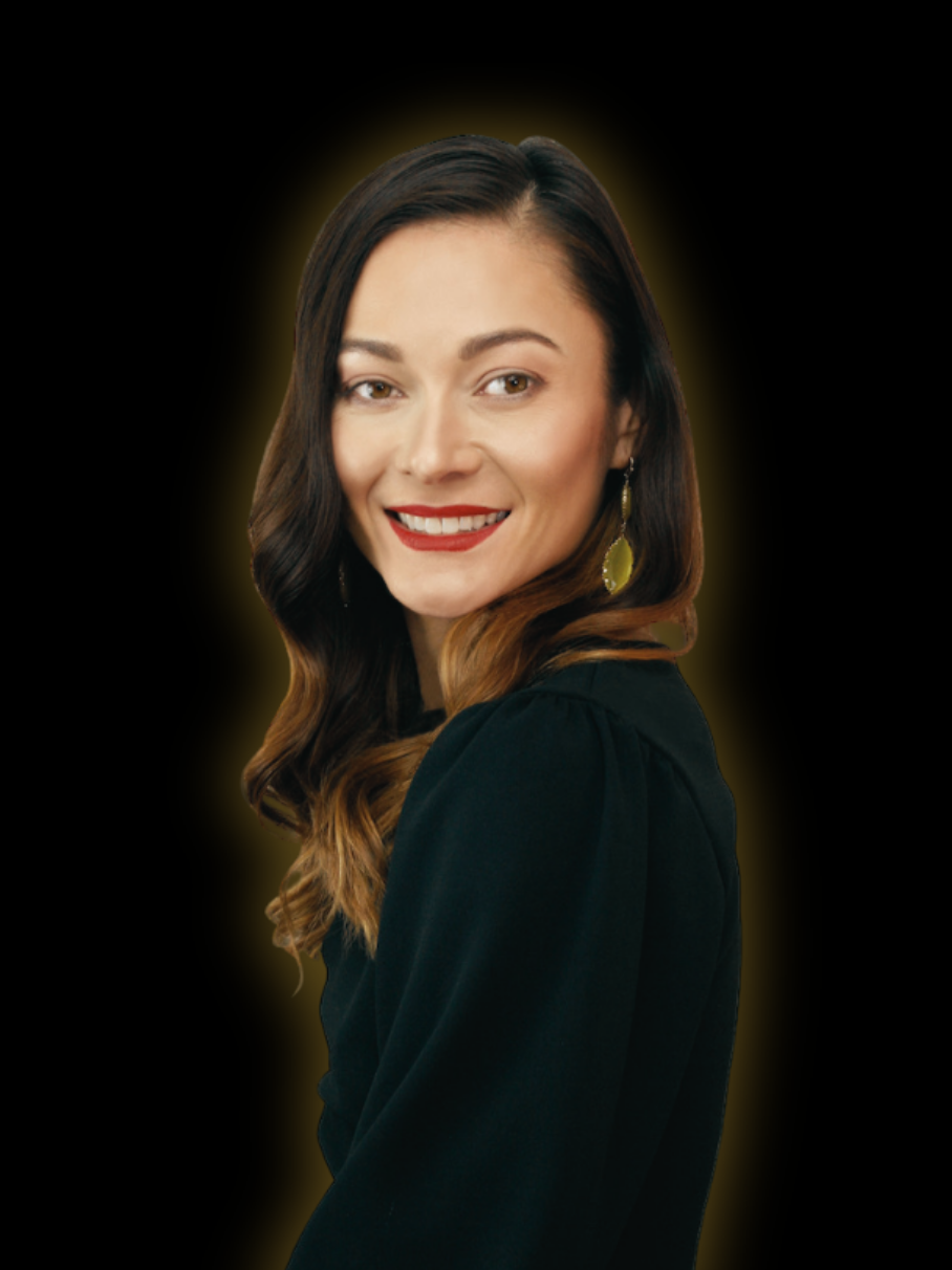 Portrait of a smiling woman with dark brown hair and red lipstick, wearing a black top and gold earrings, against a black background with a yellow glow.