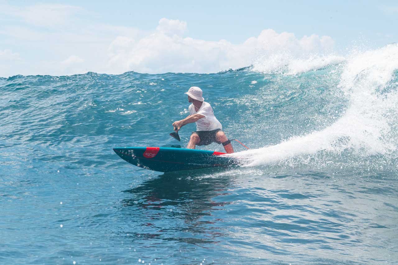 sup surfer carving down a wave while his board is on plane