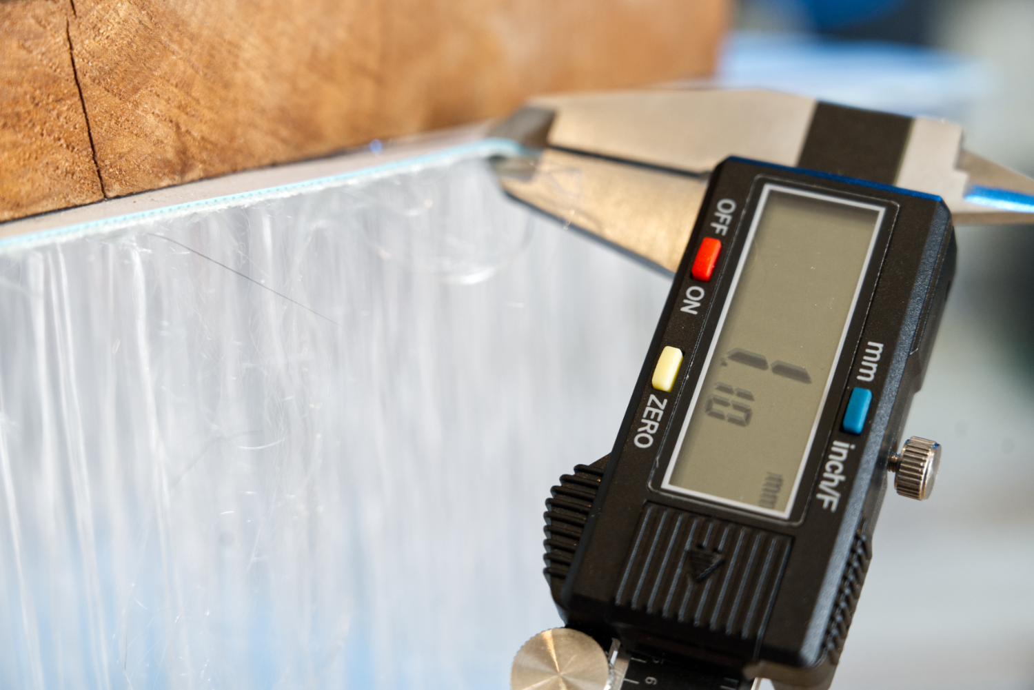 A set of digital calipers measures the thickness of an iSUP outer shell material and displays 1.10 mm.
