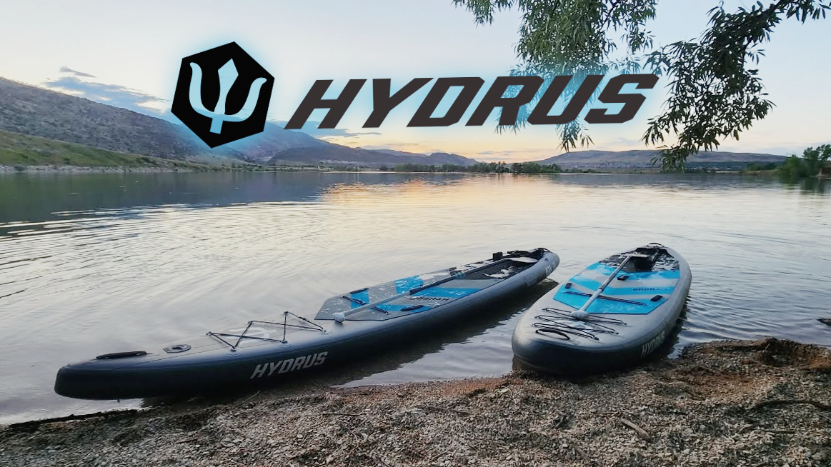 Two Hydrus iSUPs on the bank of a lake at sunset with the Hydrus logo at the top of the image.