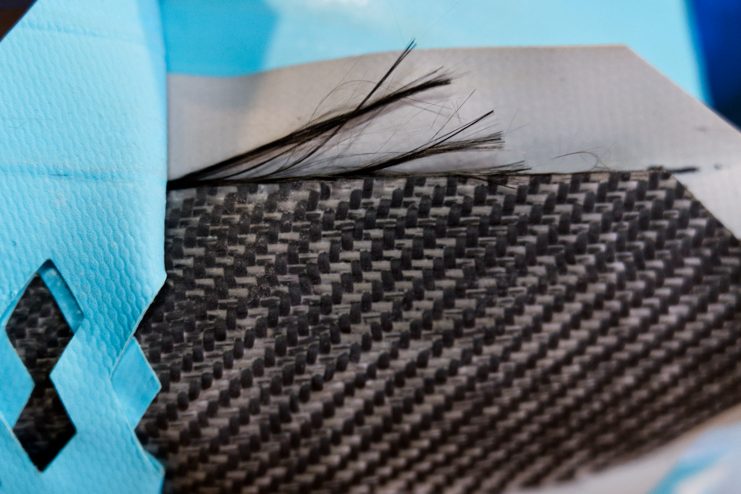 A close up image of a paddle board's carbon fiber textile reinforcement layer with each layer peeled away for visiblity.