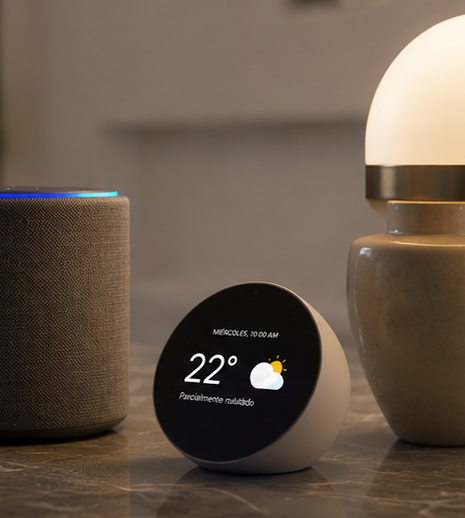 Un altavoz inteligente y un asistente digital en una mesa, mostrando el clima con 22 grados y cielo parcialmente nublado.